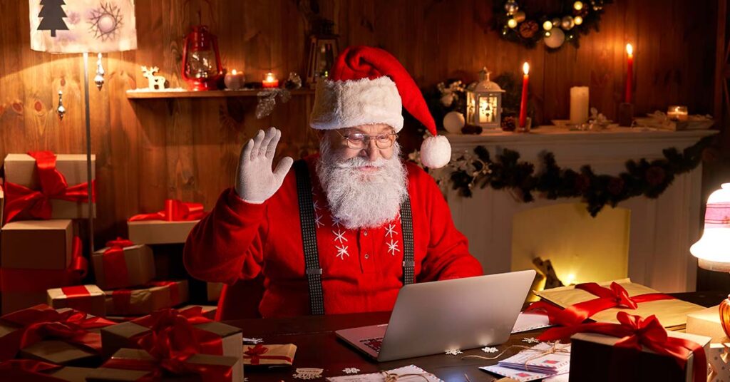 Weihnachtsman in seinem Haus vor dem Laptop