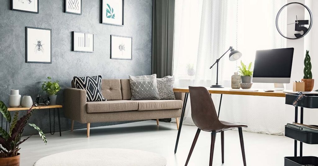 Ein großes Wohnzimmer mit Sofa, Bildern, Tischchen und Schreibtisch mit Computer für Homeoffice | Homeoffice
